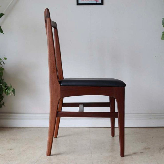 Mid-century British vintage teak dining chair with sleek tapered legs and black cushioned seat, classic Danish design.