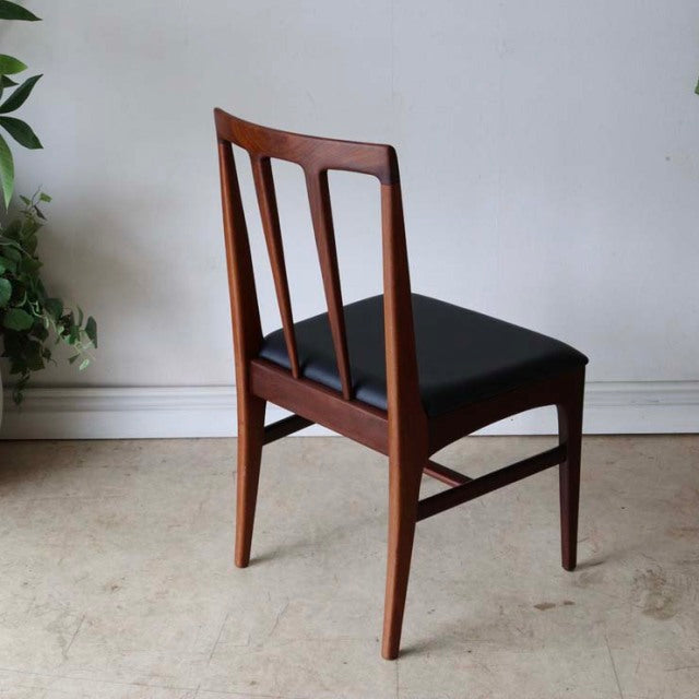 Vintage teak dining chair with British mid-century design, sleek vertical slat back and black upholstered seat, four tapered .