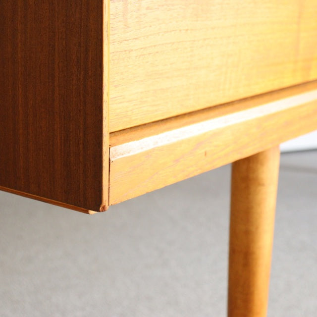 Close-up of British mid-century Austinsuite sideboard corner in warm teak with smooth wood grain, clean edges, and slender.