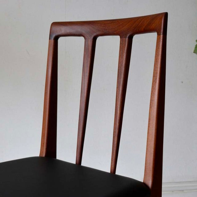 Mid-century British dining chair with teak wood frame, slender vertical back slats, and black upholstered seat.