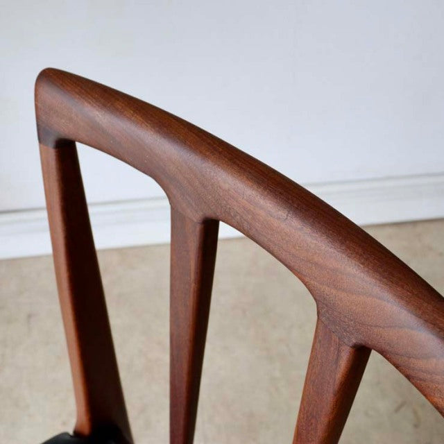 Close-up of vintage teak dining chair backrest with smooth wood grain, mid-century British Denmark style.