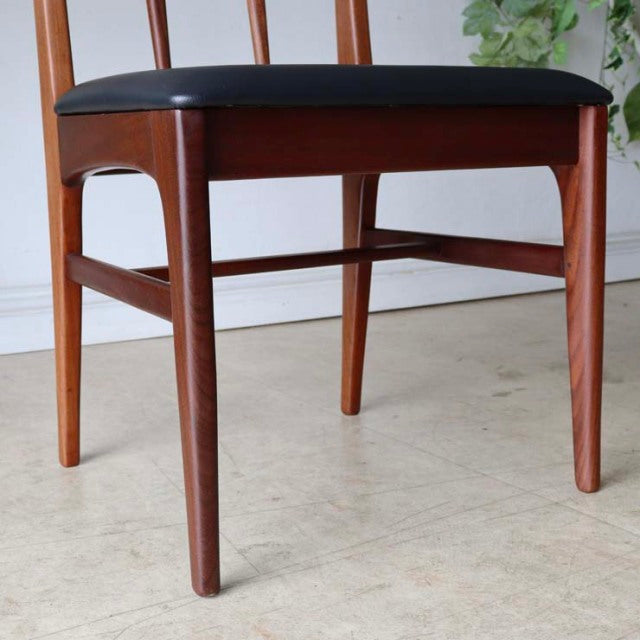 Mid-century British vintage teak dining chair with black cushioned seat and tapered legs.