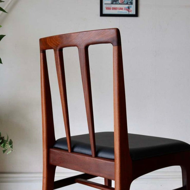 Set of four A.Younger Ltd. vintage British mid-century teak dining chairs with black leather seats and slender vertical back .
