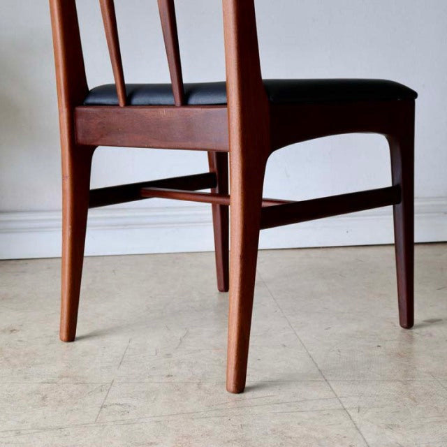 Set of four British mid-century dining chairs in teak with sleek tapered legs and vertical slat backrests, showcasing rich.