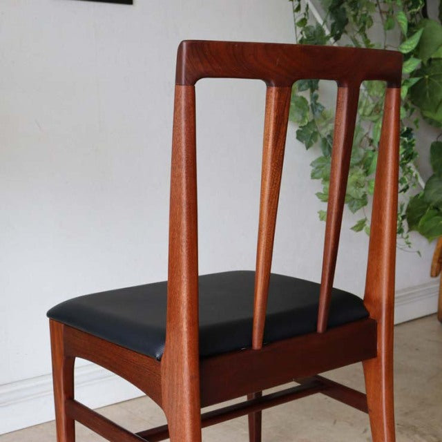 Vintage mid-century British dining chair in teak with vertical wood grain backrest and black cushioned seat.