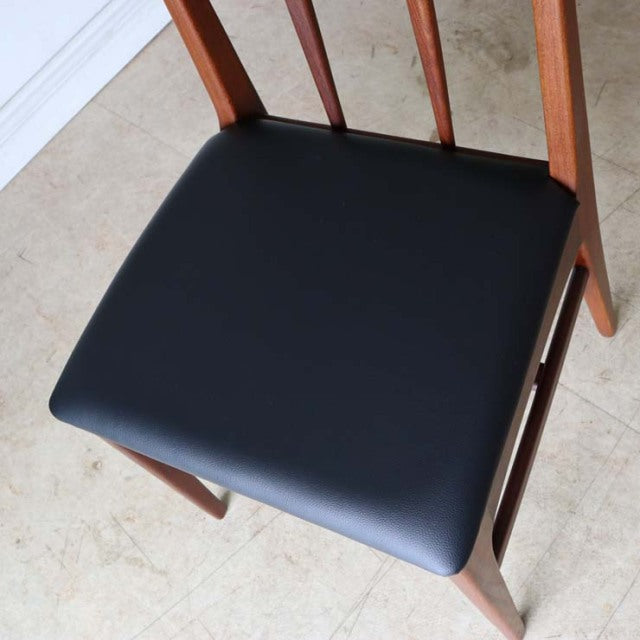 Vintage mid-century teak dining chair with black leather seat, slender legs, and British-Denmark design.