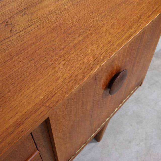 Vintage teak mid-century British sideboard corner with distinctive round wooden handle and visible wood grain.