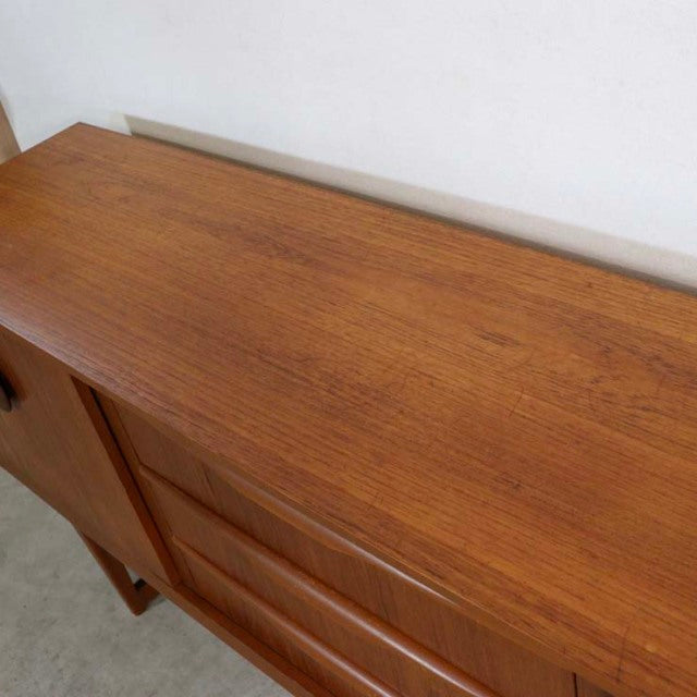 Mid-century British vintage teak sideboard with distinctive wood grain and unique angled legs.