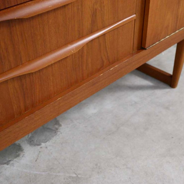 Mid-century vintage British teak sideboard with distinctive curved handle and tapered legs showing rich wood grain.
