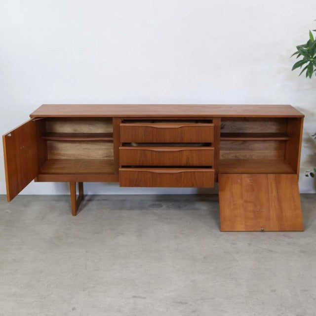 Mid-century British vintage teak sideboard with distinctive angled legs and rounded handles, open doors revealing spacious.