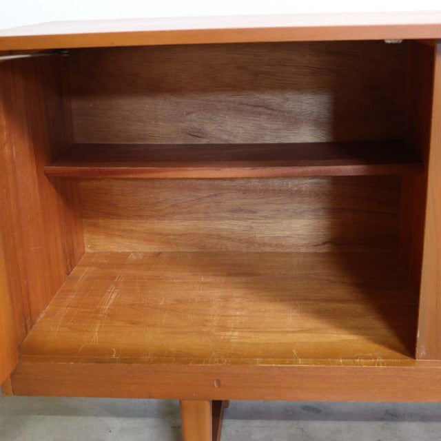 Open vintage British mid-century teak sideboard interior showing rich wood grain and smooth shelf design.