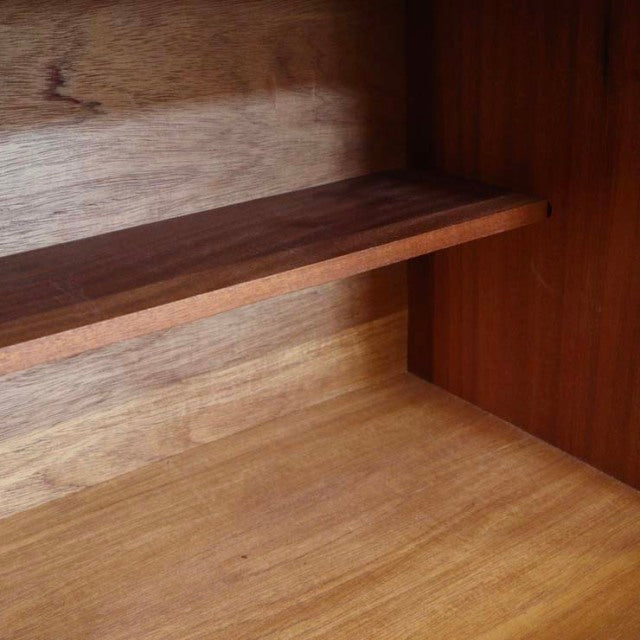 Close-up of mid-century British vintage teak sideboard interior showing rich wood grain and smooth shelf surface.