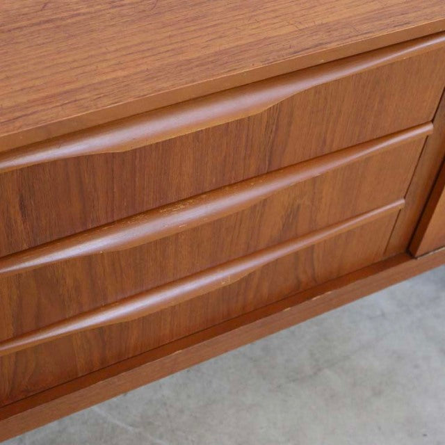 Mid-century vintage British teak sideboard with distinctive curved handles and rich wood grain texture.