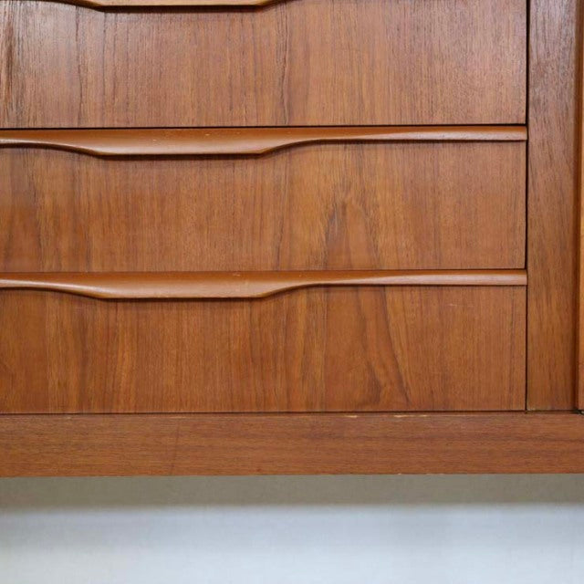 Mid-century British vintage teak sideboard drawers with smooth wood grain and integrated curved handles.