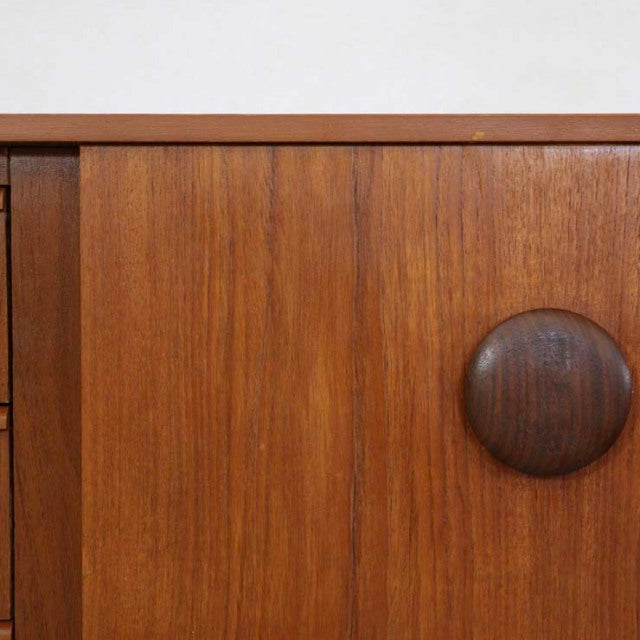 Mid-century British vintage teak sideboard door with distinctive round dark wood handle and visible grain texture.