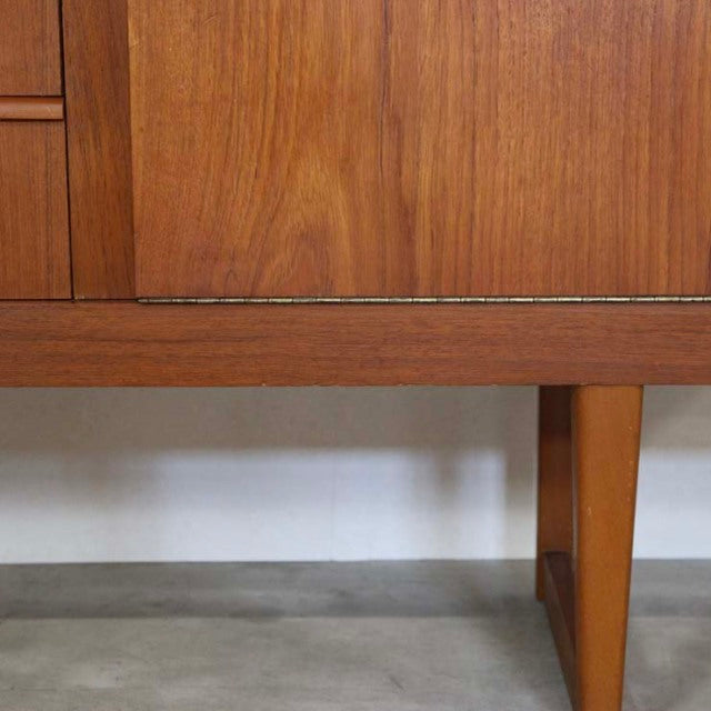 Mid-century British teak sideboard with distinctive angled legs and rich wood grain detailing from Denmark vintage collection.