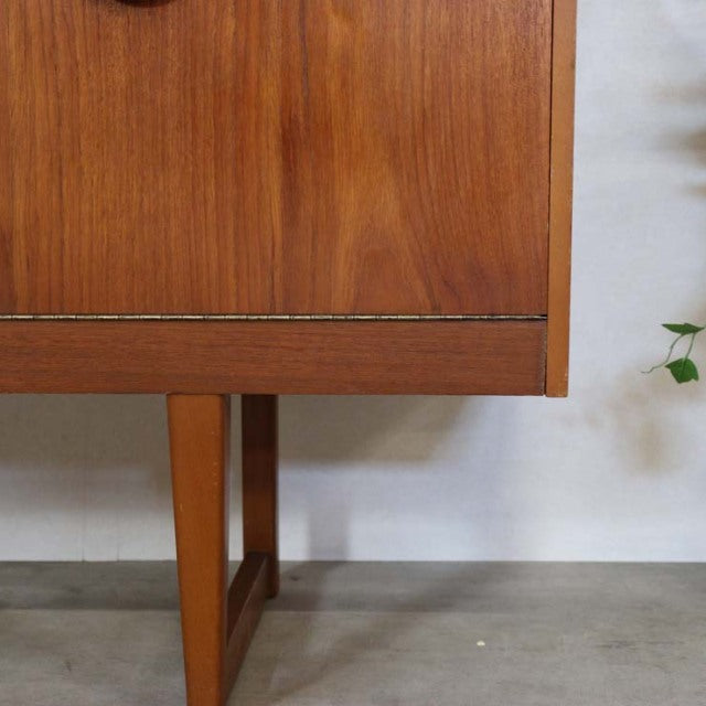 Mid-century British vintage teak sideboard corner with distinctive angled legs and rich wood grain texture.