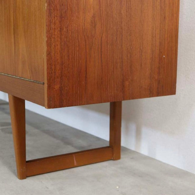 Mid-century British vintage teak sideboard with distinctive rectangular teak legs and rich wood grain finish against white.