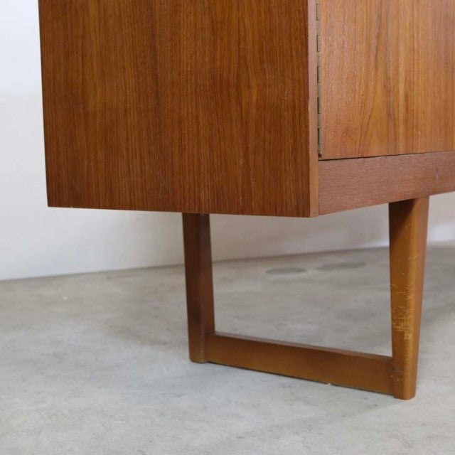 Mid-century British vintage teak sideboard corner highlighting distinctive rectangular legs and rich wood grain finish.