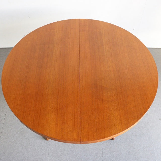 Round vintage teak dining table by Edward Valentinsen with mid-century British-Denmark design, smooth wood grain surface,.