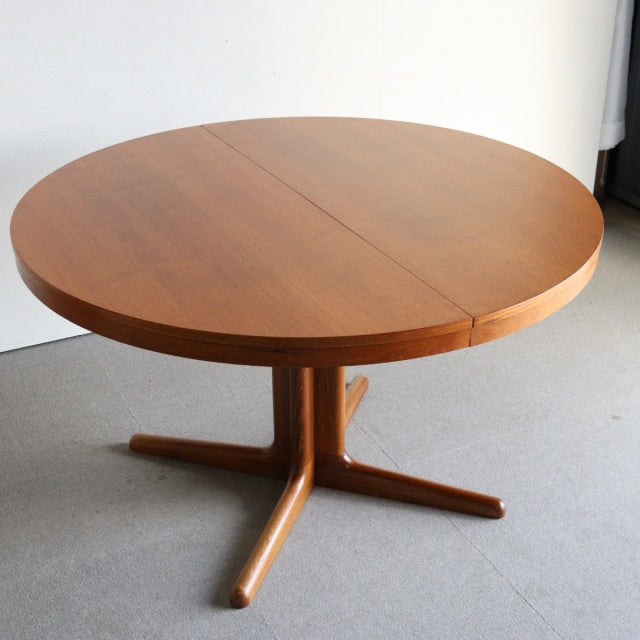 Round vintage teak dining table by Edward Valentinsen with mid-century British-Denmark design, smooth wood grain, and.