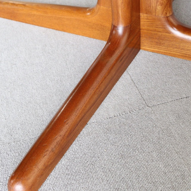 Close-up of Edward Valentinsen mid-century teak dining table leg with smooth grain and rounded edges, showcasing.