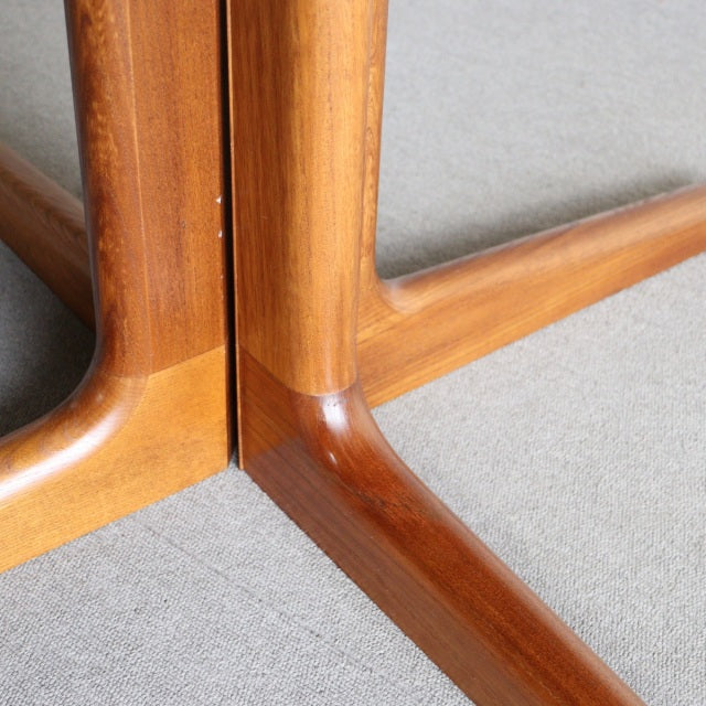 Close-up of vintage Edward Valentinsen teak dining table legs showing smooth wood grain and mid-century British-Denmark.