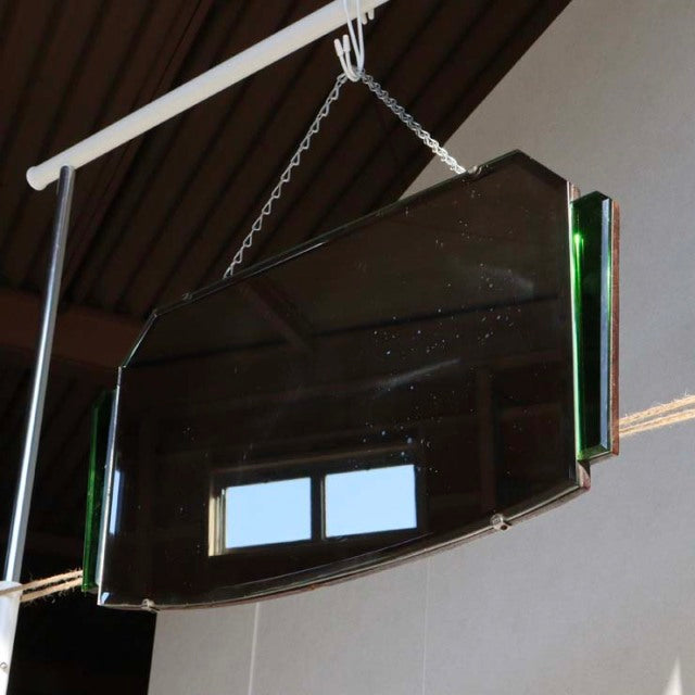 Vintage British mid-century wall mirror with teak frame and beveled green glass accents hanging by chain.