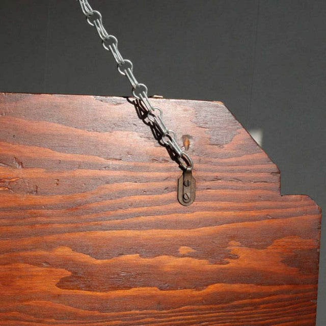 Close-up of vintage teak wood with rich grain texture and aged patina, mid-century British mirror frame hanging by metal.
