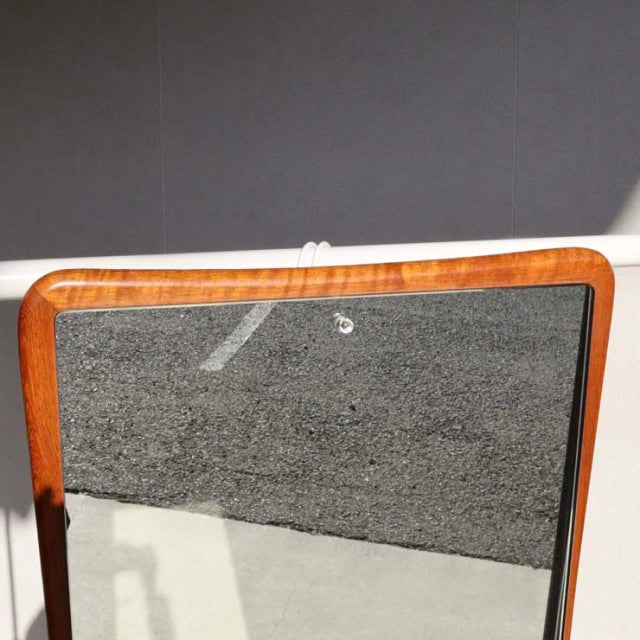 Rectangular mid-century British vintage wall mirror with rounded corners, teak wood frame showing warm grain patterns and.