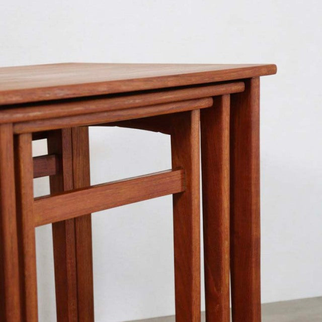 Set of vintage mid-century teak nest tables with clean lines, British-Denmark design, showcasing warm wood grain and slender .