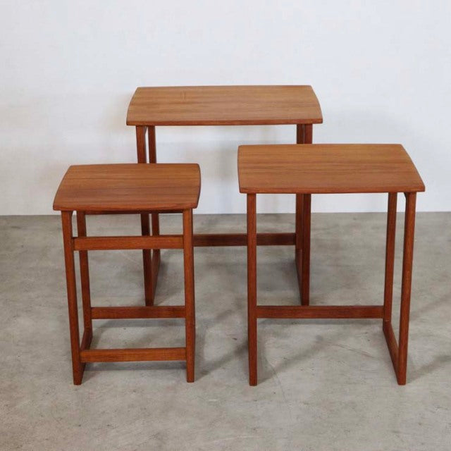 Set of three vintage teak nest tables with clean mid-century British design, visible wood grain, slender straight legs, and.