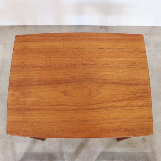Vintage teak British mid-century nest table with smooth wood grain and tapered legs.