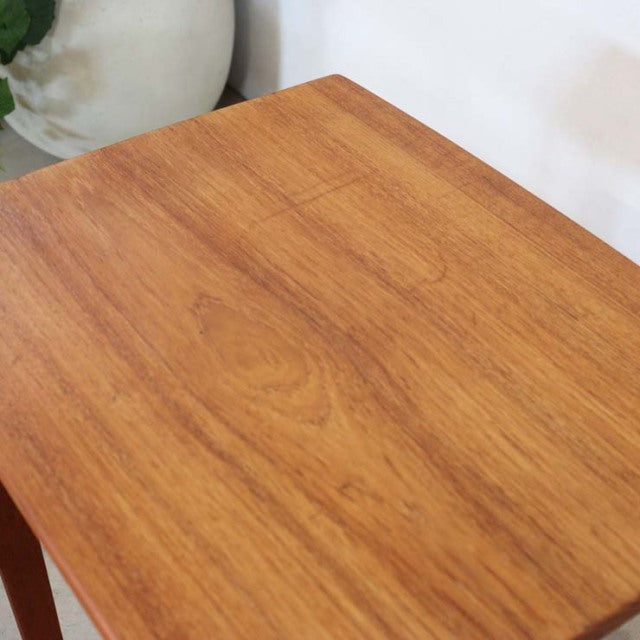 Mid-century British vintage teak nest table with smooth wood grain and rounded edges.
