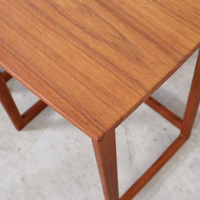 Mid-century British vintage teak nest table with rich wood grain, square top, and slender legs.
