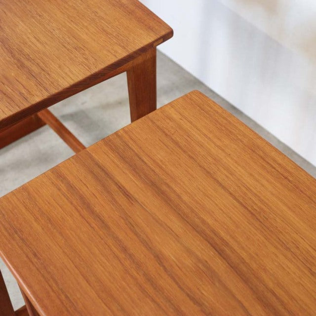 Set of two vintage teak nest tables with smooth wood grain and tapered mid-century British legs, Danish design influence.
