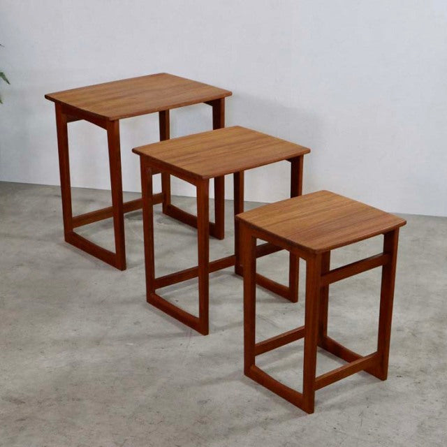 Set of three vintage British mid-century teak nest tables with clean lines, visible wood grain, and open rectangular legs in .