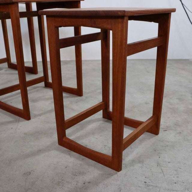 Set of mid-century vintage teak nest tables with clean lines, British-Denmark design, showcasing rich wood grain and slender .