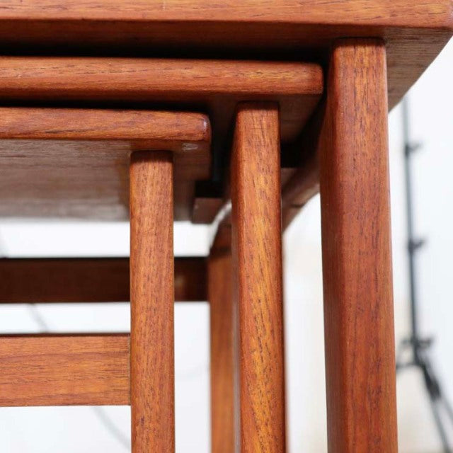 Set of vintage teak nest tables with clean lines, showcasing fine wood grain and slender mid-century British legs in Denmark .