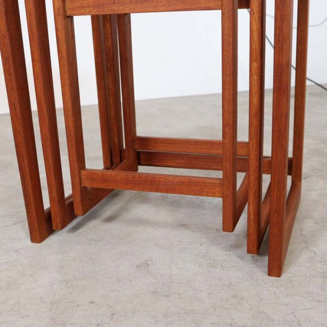 Set of three vintage teak nest tables with visible wood grain, slender square legs, and mid-century British-Danish.