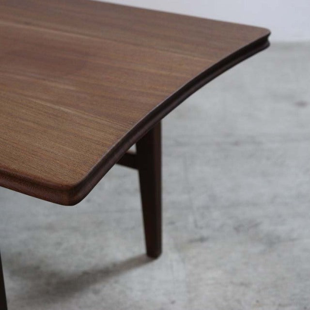 Close-up of vintage British teak mid-century coffee table corner with smooth rounded edge and visible wood grain.
