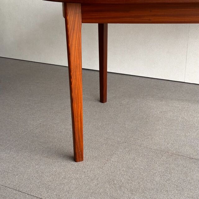 Mid-century British vintage teak dining table leg with warm wood grain and tapered design on neutral floor.