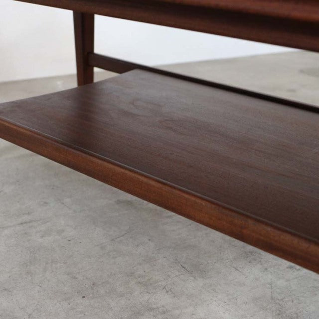 Vintage British mid-century teak coffee table with magazine rack, smooth wood grain and tapered legs.