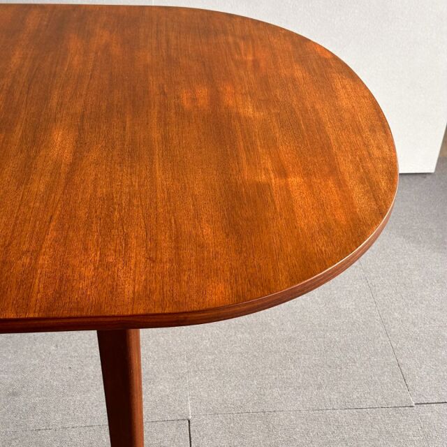 Oval mid-century vintage teak dining table top with warm wood grain and rounded edges, British and Danish design influence.
