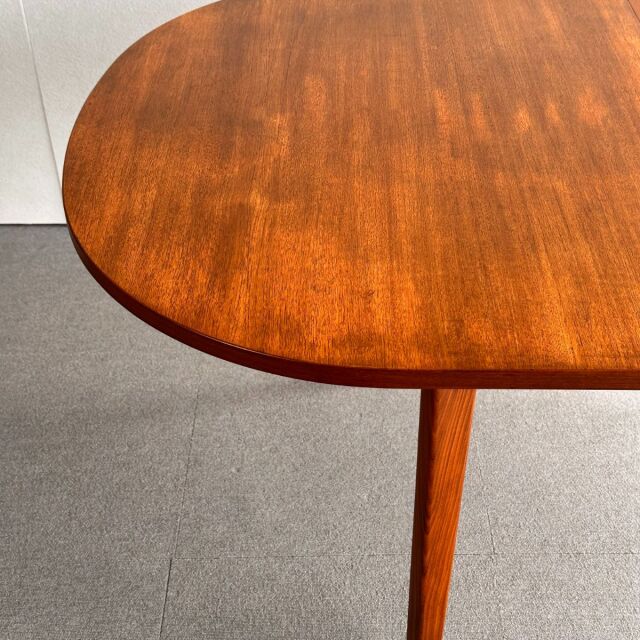 Oval vintage teak dining table with smooth wood grain and tapered mid-century British legs from Denmark.