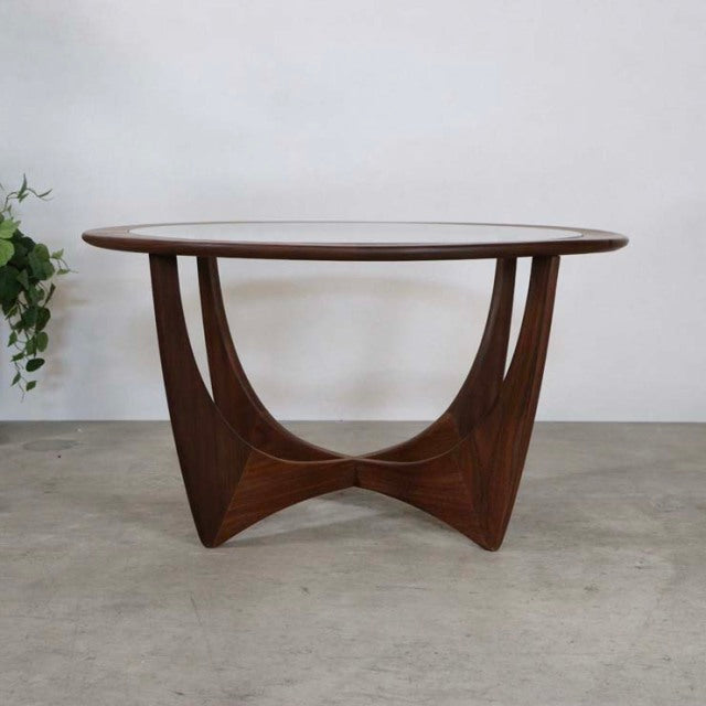 Mid-century British G-PLAN teak coffee table with smooth oval top and sculptural curved legs showcasing rich wood grain.