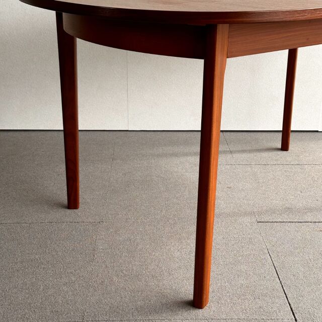 Mid-century British vintage teak oval dining table with smooth wood grain and tapered round legs.