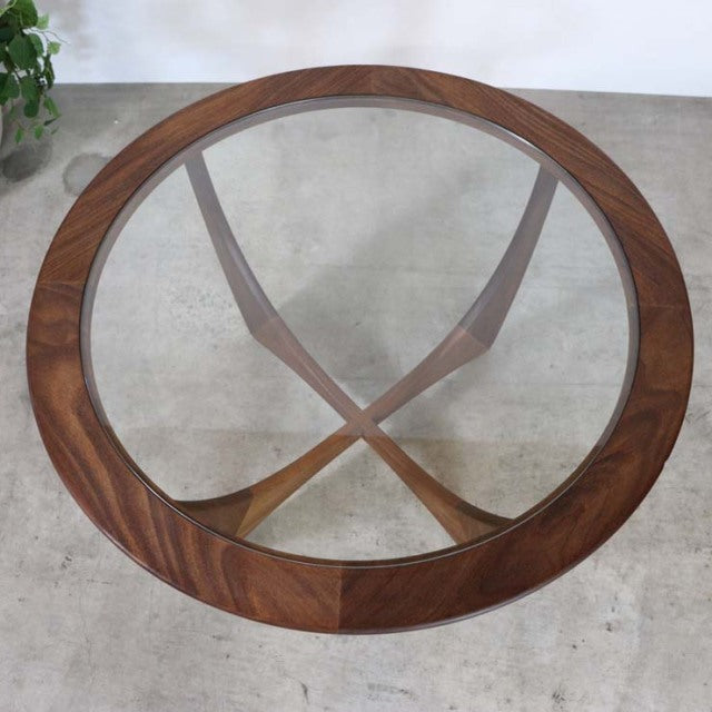 Vintage mid-century British G-PLAN teak coffee table with round glass top and crossed wooden legs.