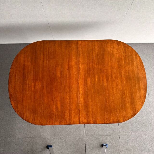 Vintage mid-century British teak oval dining table with rich wood grain and smooth rounded edges.