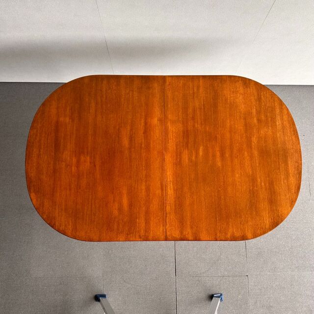 Mid-century British vintage teak oval dining table with smooth wood grain and rounded edges.